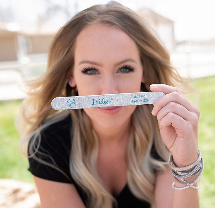 brown haired women in a black shirt holding an Iridesi zebra nail file printed with Iridesi logo, name, and grit.
