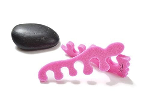 Teenie toe separators. Pink toe separators in the shape of a baby foot. White background. smooth black rock near toe separators.
