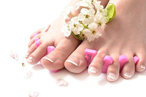 women's foot with the teenie toe separators on with a French pedicure. White background.