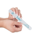 Iridesi zebra nail file in women's hands with French manicure and white background.