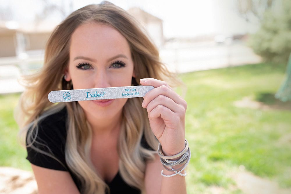brown haired women in a black shirt holding an Iridesi zebra nail file printed with Iridesi logo, name, and grit.