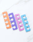 Iridesi toe separators colors are purple, blue, orange, pink on one side white on the other.