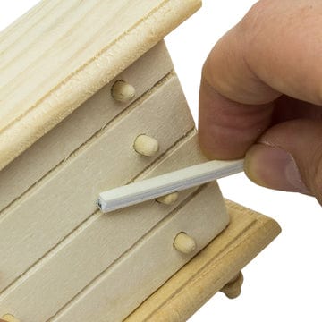 sanding sticks or twigs being used on a miniature wooden dresser