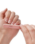 mini pink Iridesi nail files, 3.5 inches long, 1/2 inch wide, Iridesi printed logo, name and grit. White background. In a women's hands with a French manicure.