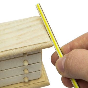 sanding sticks or twigs being used on a miniature wooden dresser