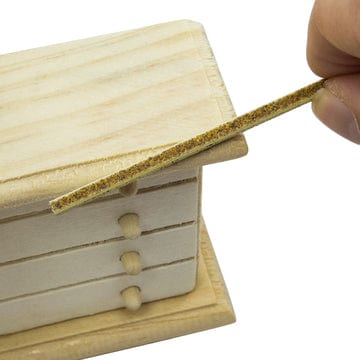 sanding sticks or twigs being used on a miniature wooden dresser