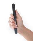 women's hand holding a black 4 way nail file, white center, round edges, white background.