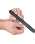 women's hand holding a black 4 way nail file, white center, round edges, white background.